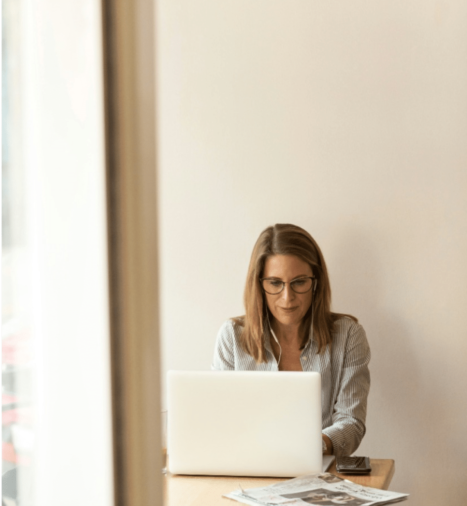 Geschäftsfrau arbeitet konzentriert an einem Laptop in einem hellen Büro, verdeutlicht den Einsatz digitaler Tools für effiziente Unternehmensprozesse.