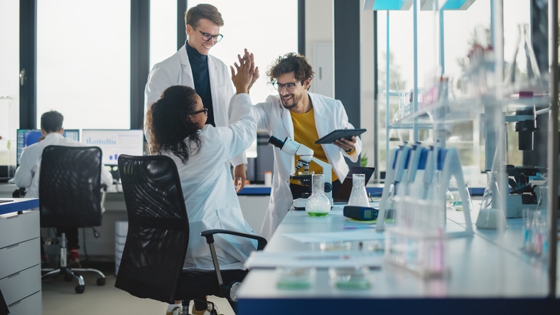 a group of people in lab coats giving each other a high five